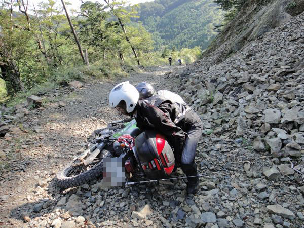 荒れた斜面でバイクを起こす
